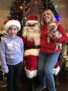 A mom, daughter and dog posing for a photo with Santa