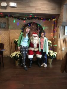Two young girls taking a photo with Santa.